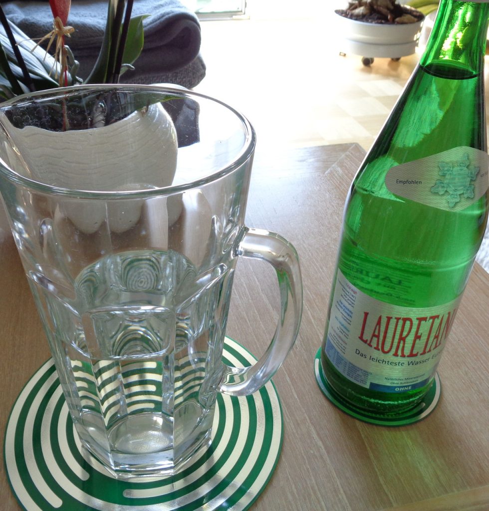 Glaskrug auf grün-weißer Energie-Scheibe, daneben grüne Wasserflasche