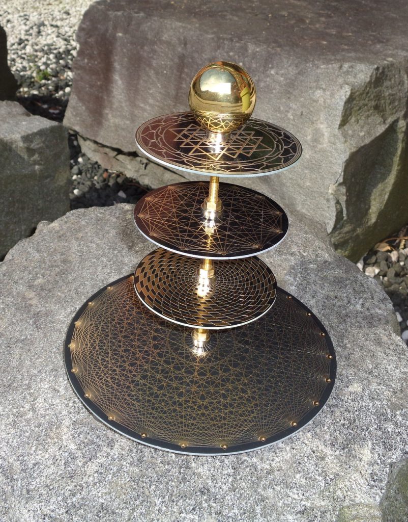 Tesla-Antenne-Nova-Sunra: Tesla-Antenne mit goldener Kugel und geometrischen Mustern auf Felsblock