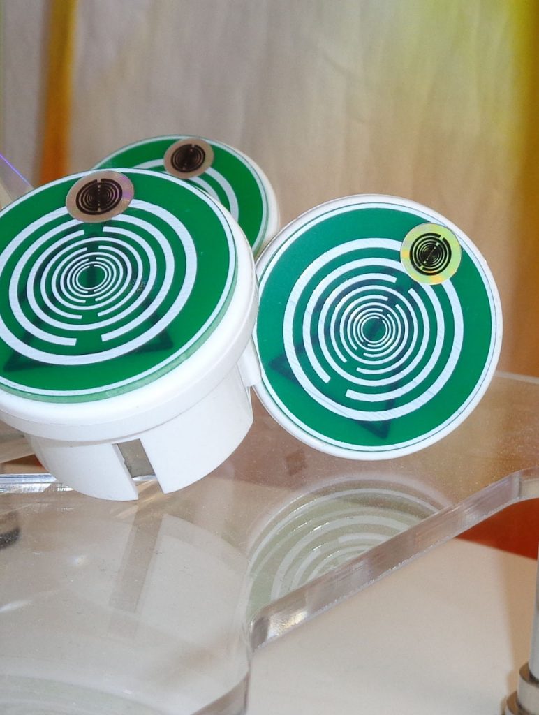 Polari-Harmonie-Stecker 2.0: Drei grün-weiße Energie-Stecker mit Spiralmuster auf transparentem Untergrund