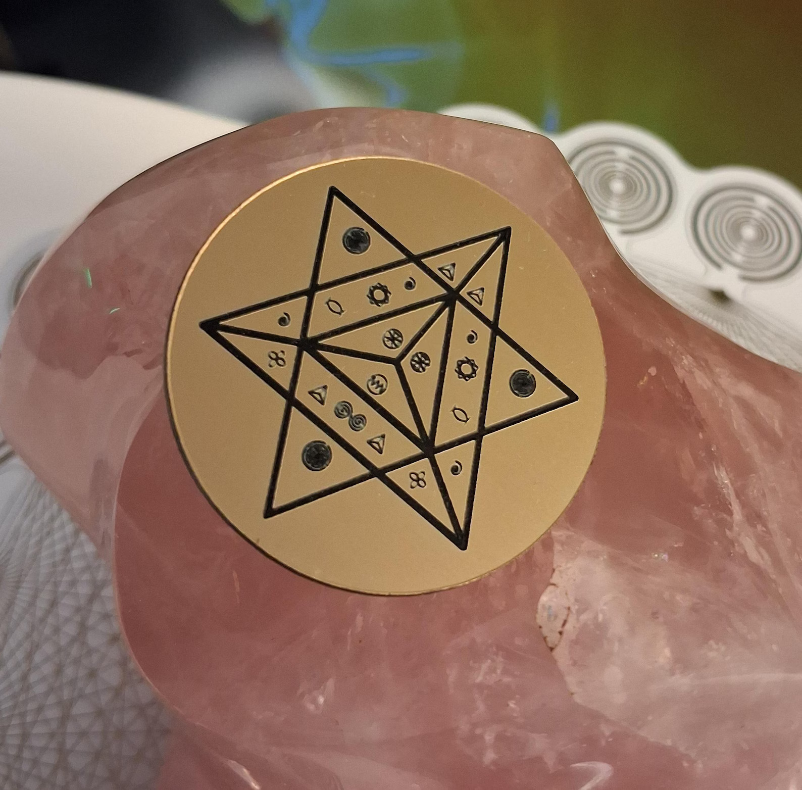 Goldene Energie-Scheibe mit schwarzem Sternsymbol auf rosafarbenem Kristall