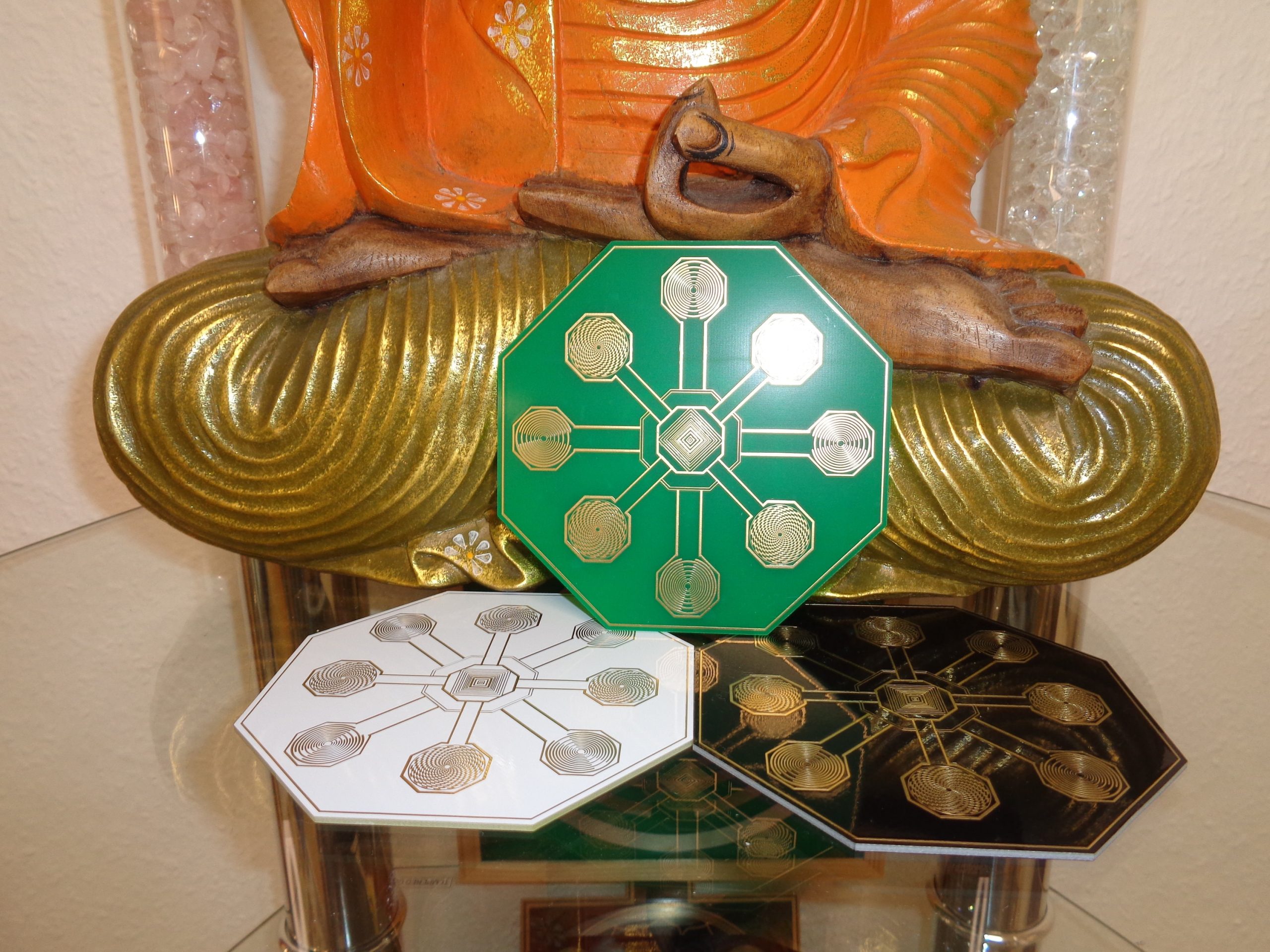 Drei achteckige Energie-Scheiben in Grün, Weiß und Schwarz vor Buddha-Statue