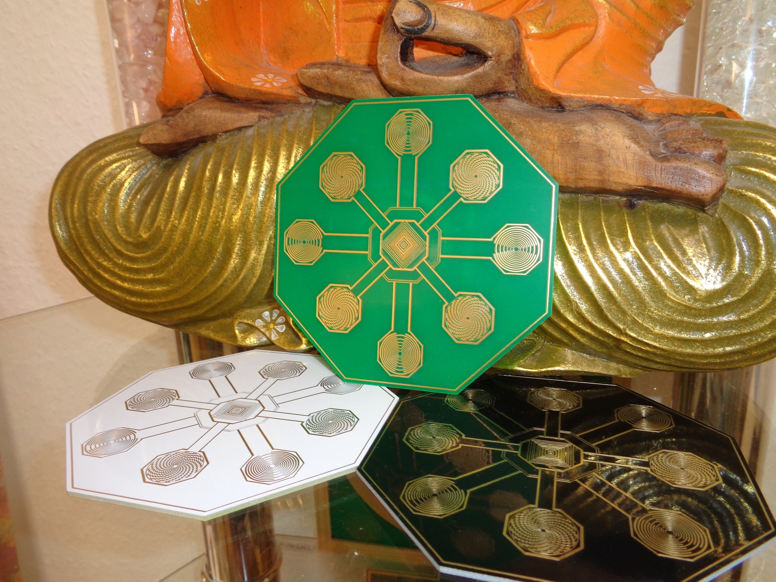 Dreifarbige Energie-Scheiben mit goldenen Mustern vor Buddha-Statue