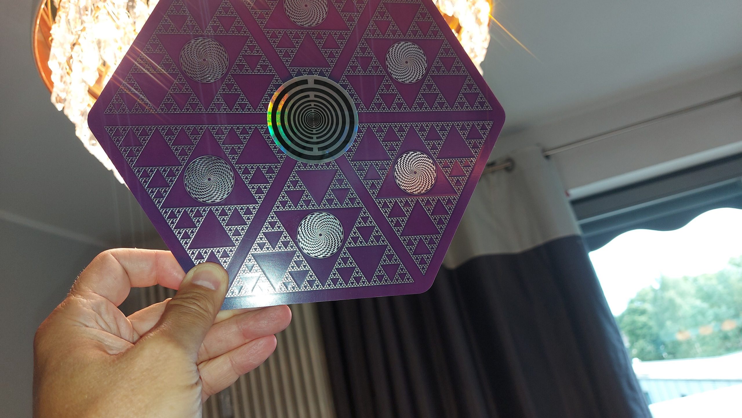 Sechseckige lila Energieplatte mit Dreieck- und Spiralmuster, Hand hält sie hoch