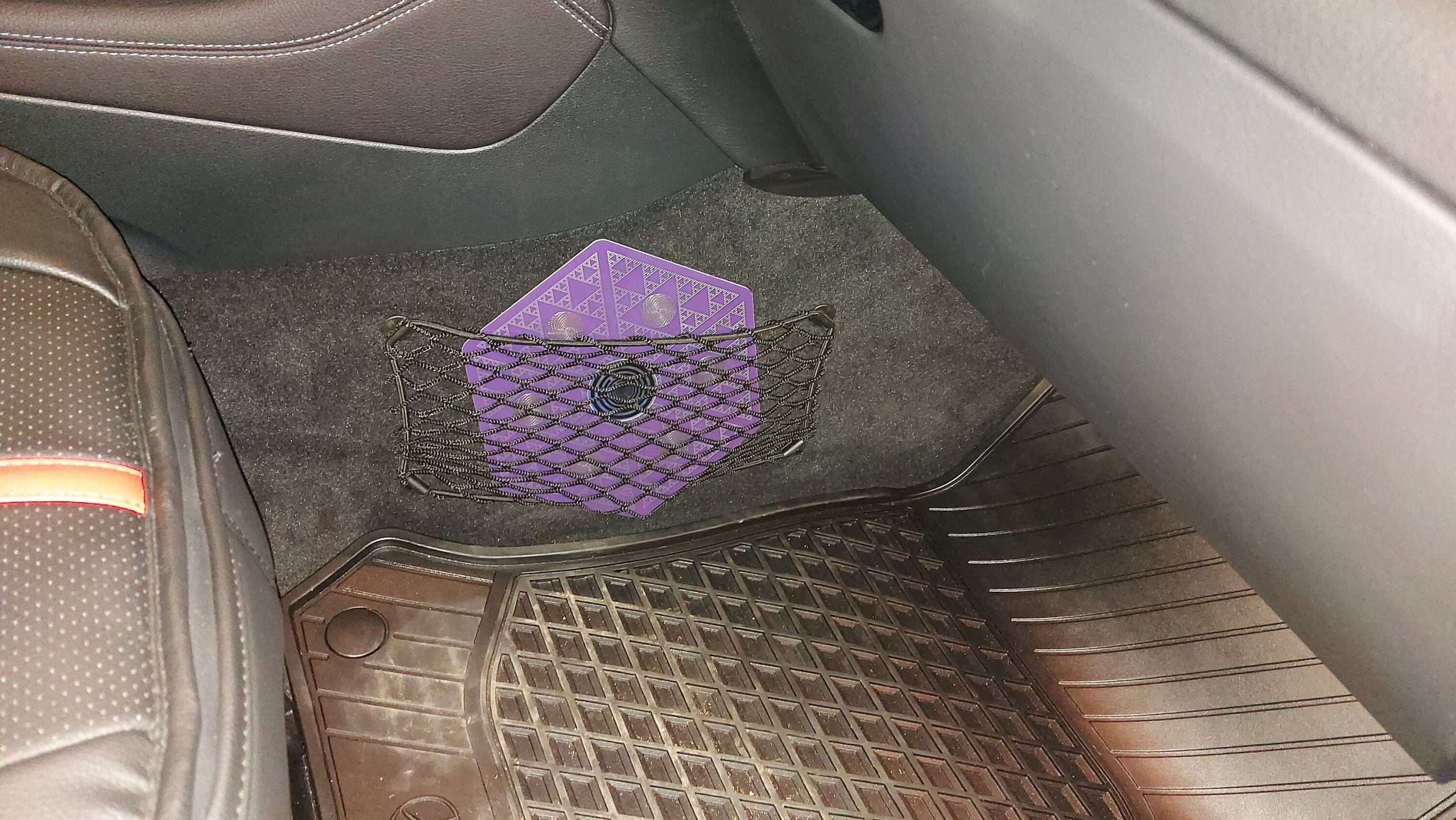 Lila Energieplatte mit Dreiecksmuster im Auto-Fußraum unter Netzfach