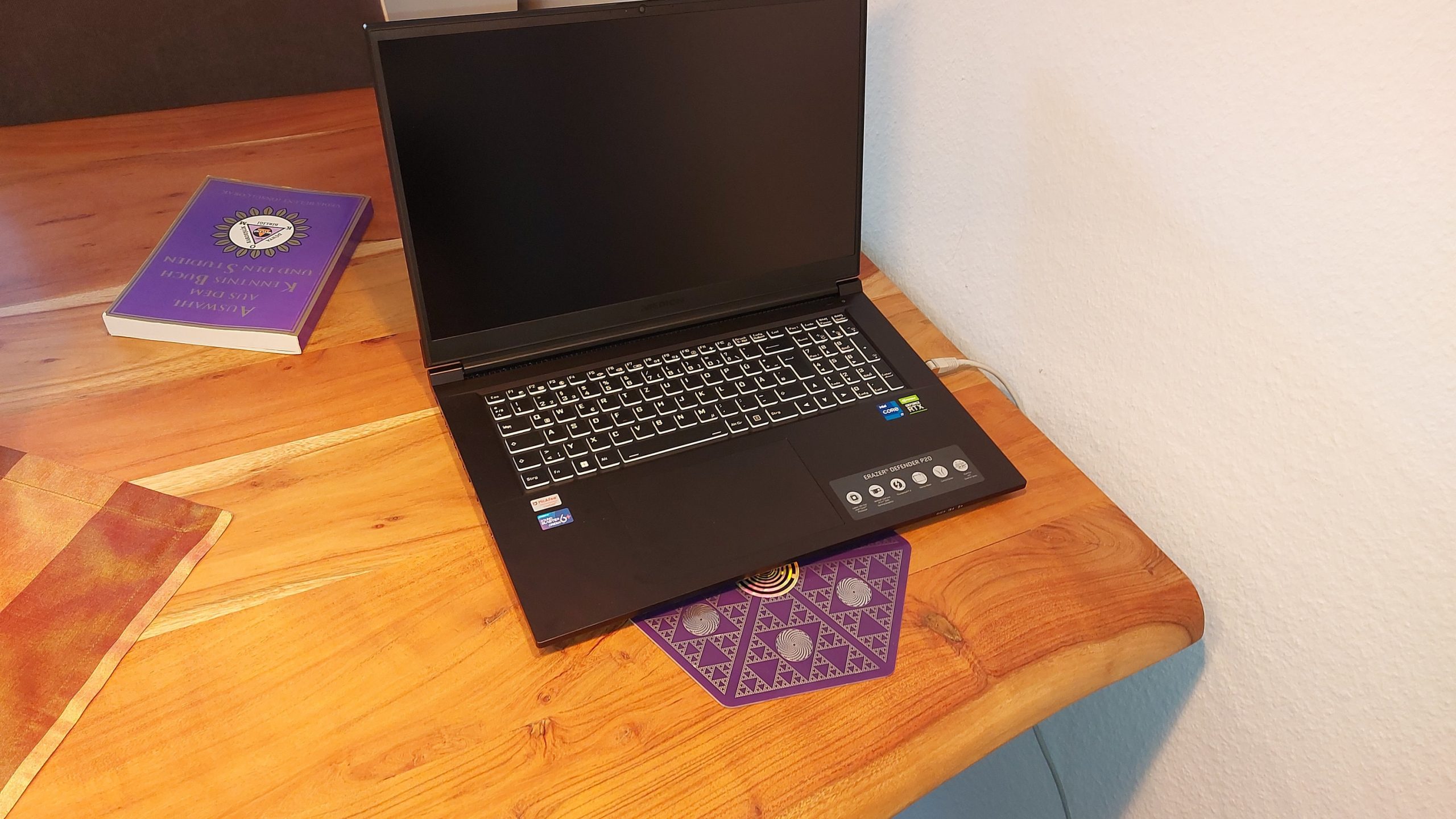 Laptop auf lila Energieplatte mit geometrischen Mustern auf Holztisch